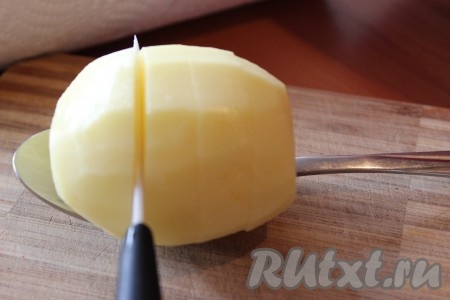 Положить клубень картофеля в столовую ложку, далее сделать поперечные надрезы по всей поверхности картошки на расстоянии 0,5 сантиметров, не дорезая до низа. Эта небольшая хитрость поможет нам аккуратно разрезать картофель и тем самым у нас получится 