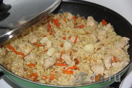Поверх риса выложить очищенные зубчики чеснока. Накрыть сковороду крышкой. Как только плов с куриной грудкой закипит, убавить огонь до минимума и готовить, примерно, 25 минут. Вода полностью впитается в рис.