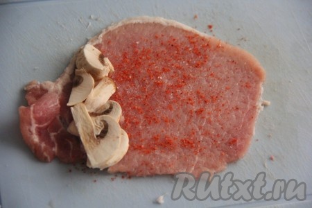 На край каждого кусочка отбитого мяса положить нарезанные грибы.
