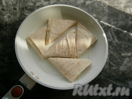 Разогреть сковороду с небольшим количеством растительного масла, выложить на неё треугольники из лаваша с колбасой и сыром.

