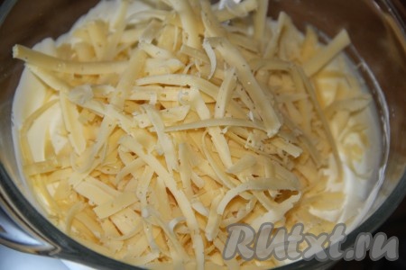 Сыр натереть на тёрке. Большую часть натёртого сыра добавить в смесь сметаны и майонеза, перемешать. Оставшийся сыр понадобится для посыпки пельмешек перед запеканием.
