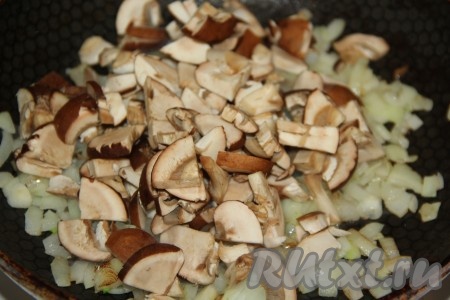 Шампиньоны промыть, нарезать на пластинки и выложить грибы в сковороду с обжаренным луком. 