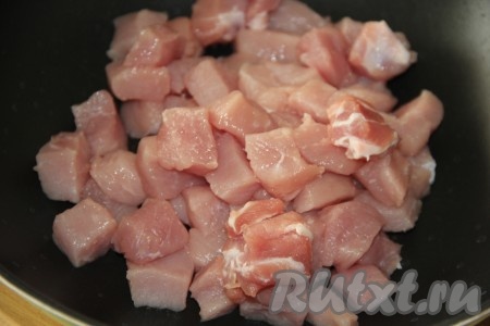 В другую сковороду влить растительное масло, выложить мякоть свинины, нарезанную на кубики размером 2х2 см.
