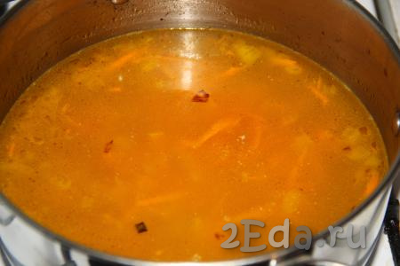 Влить в кастрюлю процеженный рыбный бульон (если вы обжаривали овощи в сковороде, то добавьте их в кастрюлю с бульоном), поставить на огонь, довести до кипения.
