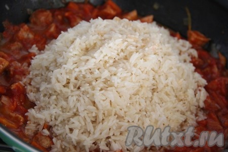 Добавить распаренный рис в сковороду к мясу и тщательно перемешать.