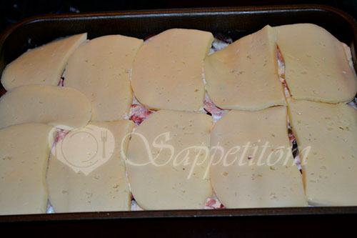 Затем форму вынимаем из духовки, раскладываем сыр нарезанный пластинами.