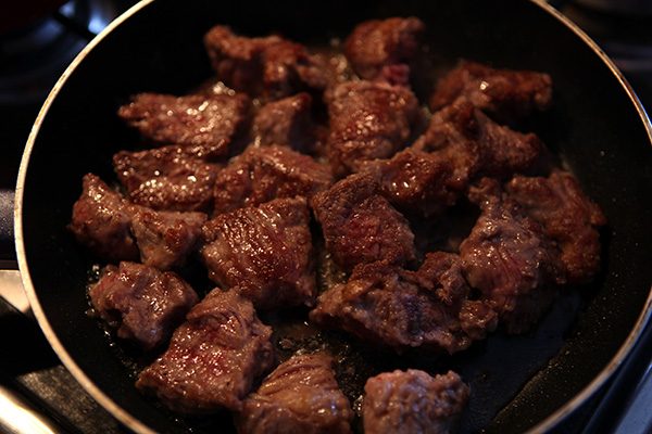Обваливаем куски мяса в муке, приправляем солью и перцем, обжариваем их на масле в отдельной сковороде со всех сторон до золотистого цвета.