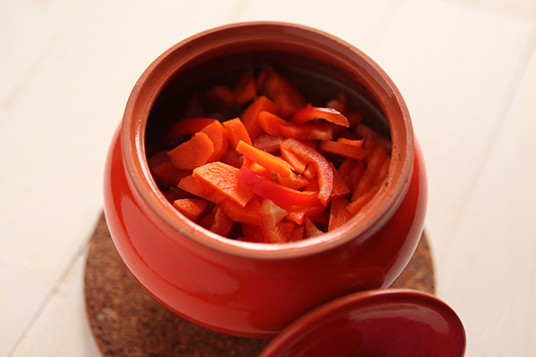 Добавляем морковь, сладкий перец и помидоры вместе с выделившимся соком в горшочки и запекаем еще в течение 20 минут.
