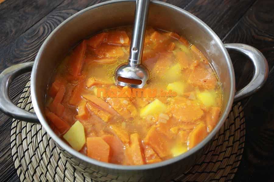 кастрюля с овощным супом и погружным блендером на столе