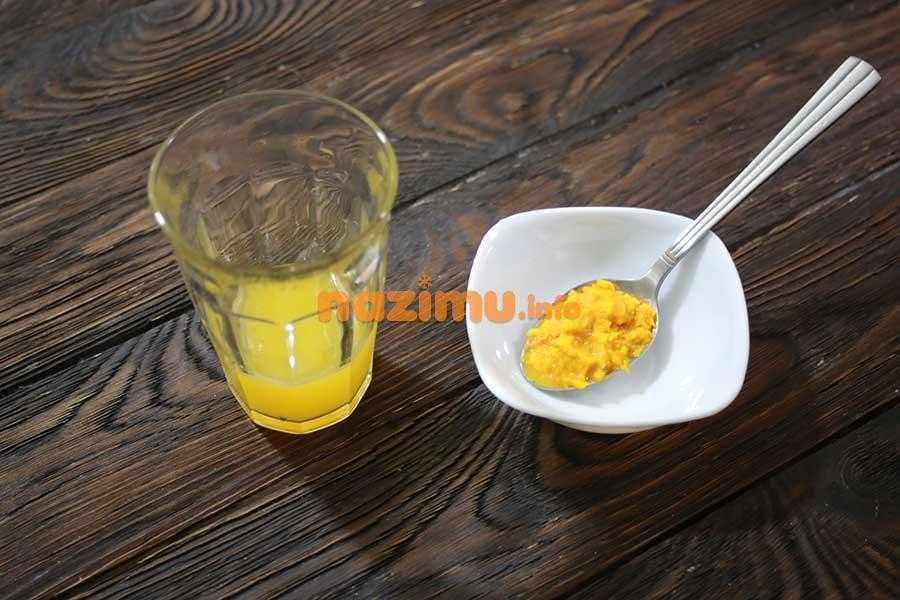 граненый стакан с апельсиновым соком, рядом измельченная на терке апельсиновая цедра в ложке