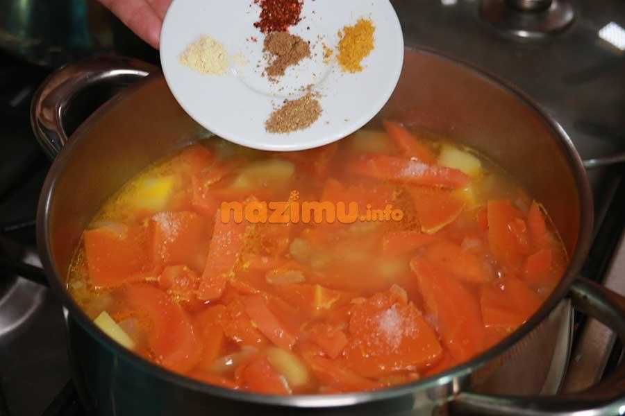 кастрюля с овощным бульоном из моркови и картошки, над ней тарелочка со специями