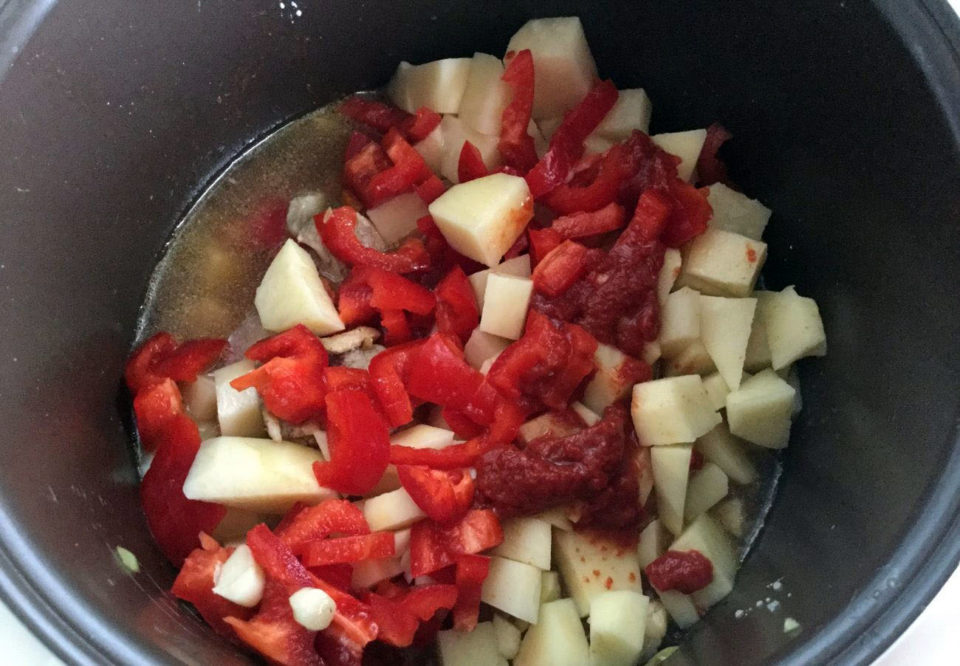 Выкладываем к мясу картофель, перец и чеснок, добавляем томатную пасту, солим и заливаем водой